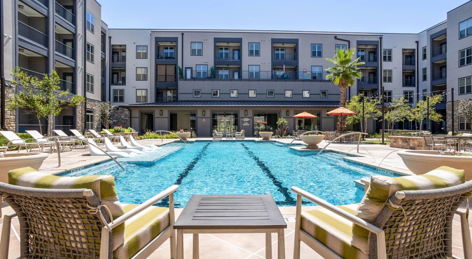 Relax and unwind poolside a pool with chairs around it